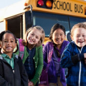 kids smiling in front of school bus